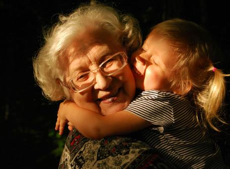 A smiling grandmother being hugged by her laughing granddaughter
