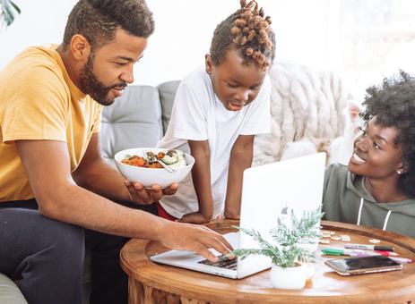 A father on a laptop with his son and partner beside him