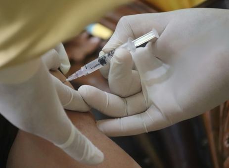 A nurse in gloves giving a vaccination in the upper arm